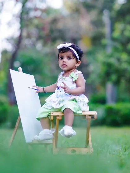 A full view of our little artist, ready to create her first masterpiece. Outdoor shoots like this allow for beautiful, natural lighting and candid moments.