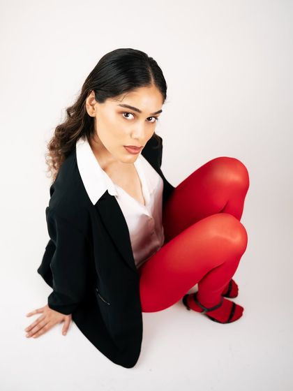 An overhead shot creating a unique perspective for this studio look. The composition, with the model looking up at the camera, is engaging and highlights the bold styling with the red tights.