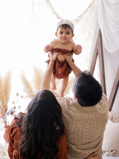 The joy of parenthood. This candid shot captures a mother and father lifting their baby girl, creating a moment of pure happiness and playfulness.
