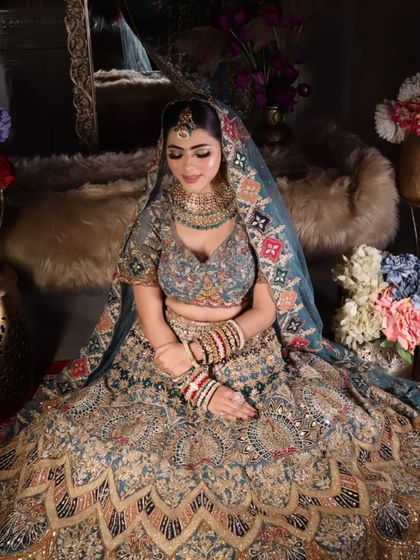 A high-angle shot of the bride seated, giving a full view of the stunning lehenga and the beautiful decor.