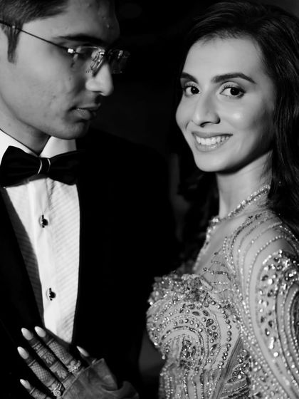 A classic black and white close-up, the bride smiling at the camera while the groom looks at her lovingly.