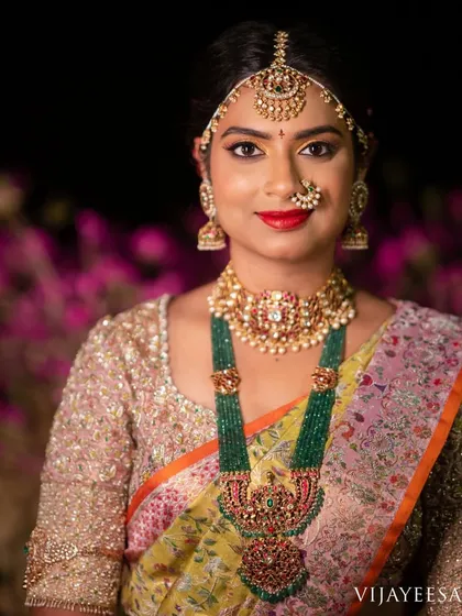 A close-up of the bride's reception look, highlighting the intricate embroidery on her blouse and her stunning emerald necklace.