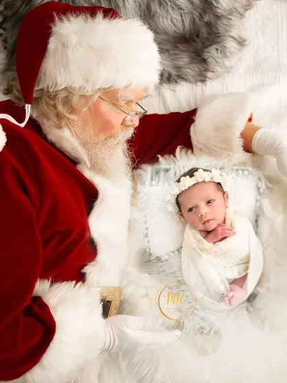 A magical Christmas moment with Santa Claus looking down at a peacefully swaddled newborn baby.