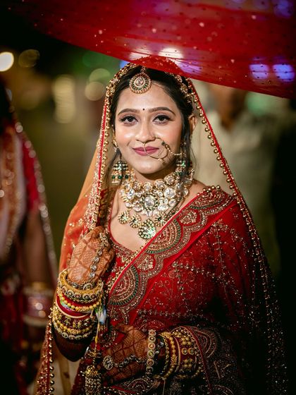 A timeless portrait of the bride under her veil. The lighting is focused to highlight her serene expression and the exquisite details of her jewelry and makeup.