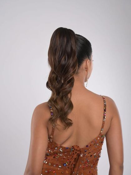 A glamorous high ponytail with soft, bouncy curls. This is a perfect party-ready hairstyle that is full of life and movement.
