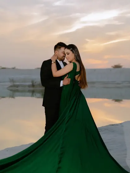 An intimate and romantic pose as the sun sets over the water. The soft, warm light and the couple's closeness make this a perfect silhouette-style pre-wedding photo.