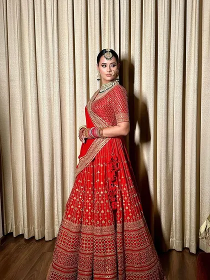 A classic bridal look for a Sabyasachi bride. The sleek low bun adorned with a gajra of baby's breath is the epitome of traditional elegance.