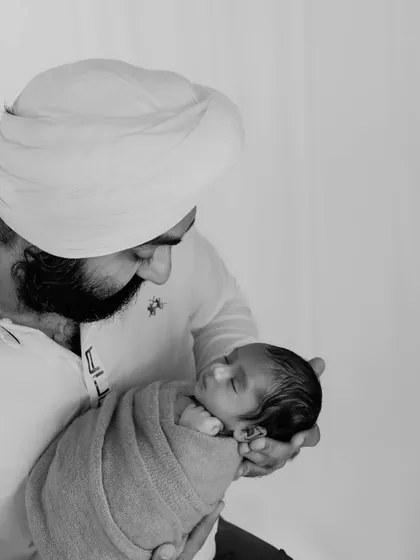 A timeless black and white version of a father gazing at his newborn. Monochrome photography often enhances the emotional depth of a portrait.