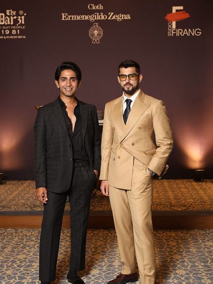 Two guests at our Zegna event, each displaying a unique sense of style. One wears a modern, textured all-black suit, while the other opts for a classic double-breasted silhouette.