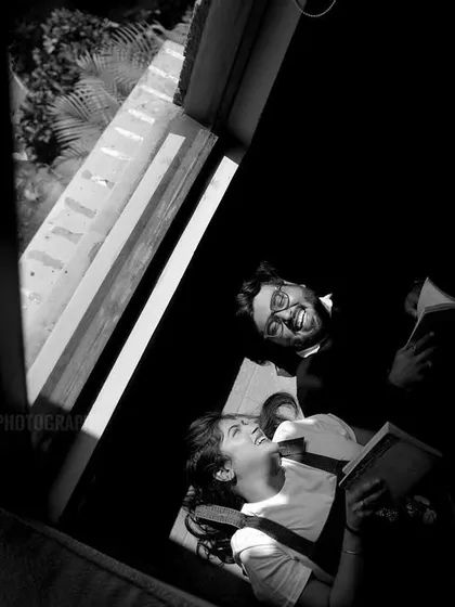 A playful and candid moment captured from above in black and white, showing the couple's joyful interaction.