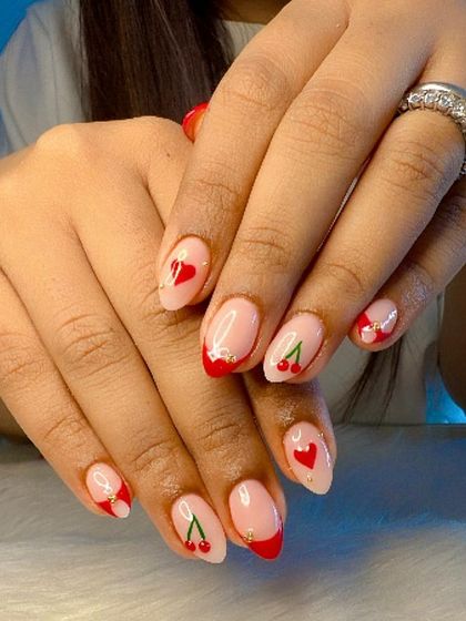 A cute set with red French tips and accent nails featuring hand-painted cherries and hearts.