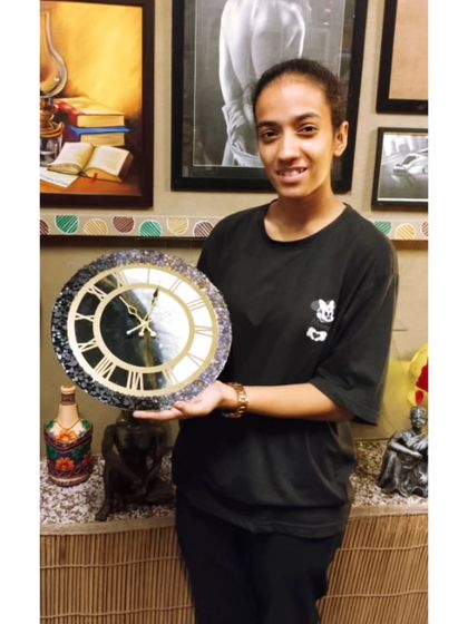 A student showcasing the elegant resin clock she created in our workshop. We guide you through the entire process, from pouring to assembly.