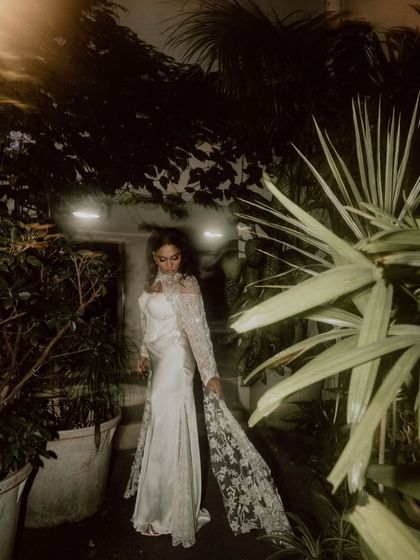 A moody, cinematic portrait of the bride in her white gown, walking through a garden at night.