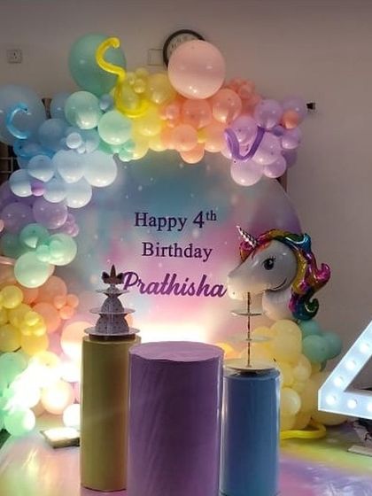 A dreamy unicorn theme for a 4th birthday, with a pastel rainbow balloon arch, a unicorn head prop, and a large light up number '4'.