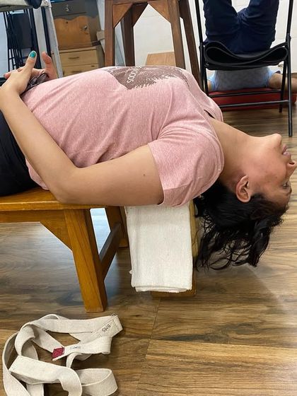 A student in a simple supported backbend on a bench. Even a simple setup like this can provide immense relief to the back and open the chest.