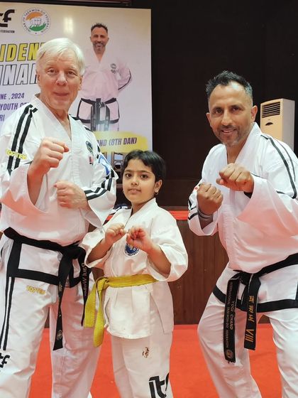 A young student gets the opportunity to pose with ITF President Grandmaster Paul Weiler and Master Yogi Chand.