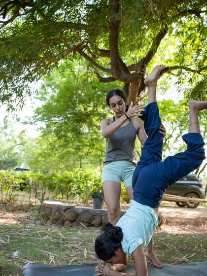 Assisting a student with a forearm stand during a retreat. My goal is to help you overcome fear and find your strength, offering support and encouragement as you explore new possibilities in your practice.