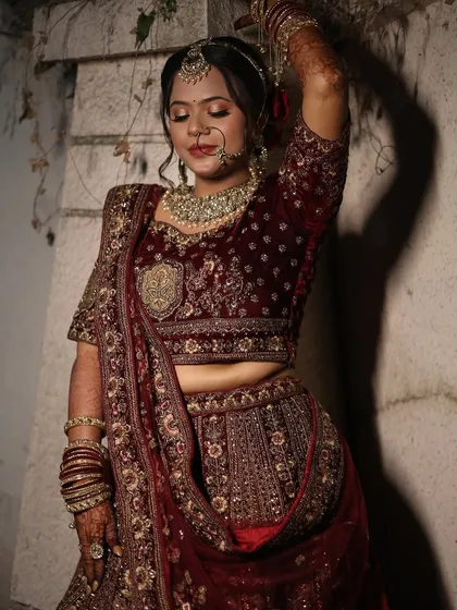 An artistic pose showcasing the intricate details of the lehenga and the bride's elegant makeup.