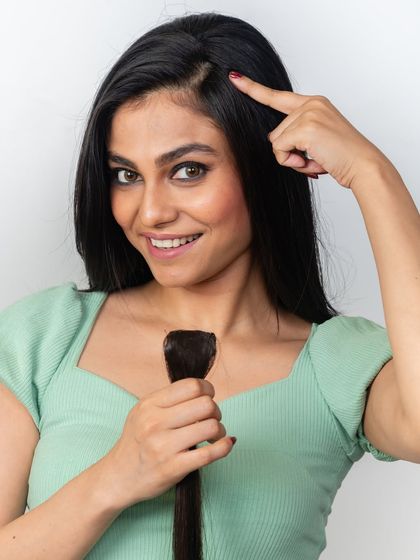 Pointing to her natural parting, this model shows where a side bang or face framer would go. These pieces are designed to cover areas of thinning for a fuller look.