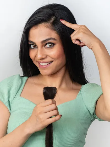 Pointing to her natural parting, this model shows where a side bang or face framer would go. These pieces are designed to cover areas of thinning for a fuller look.