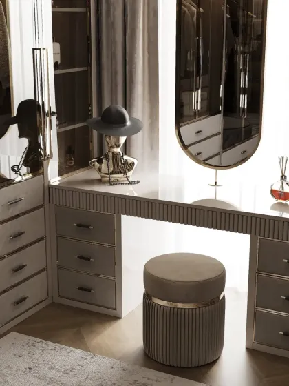 A close-up of the vanity area in the moody closet, showing the reeded drawer fronts and elegant stool. This detail shot highlights the sophisticated textures and finishes used.