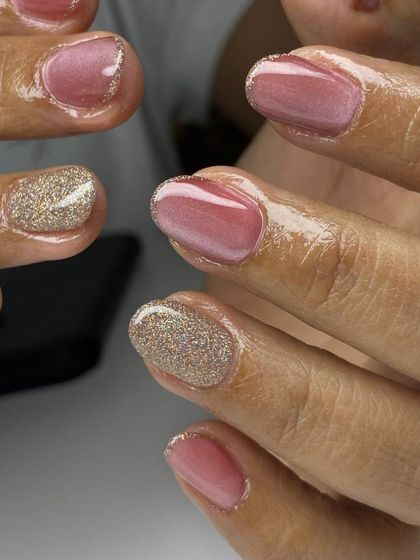 A chic and sparkling manicure combining a shimmery pink polish with full-coverage gold glitter accent nails. The contrast is both elegant and glamorous.
