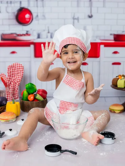 A happy wave from the star of the show! This toddler chef portrait is full of energy and personality.