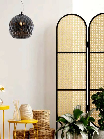 A spherical pendant with a patterned black glass finish adds a touch of graphic intrigue. This fixture shines brighter by casting unique shadows, making it a piece of functional art.