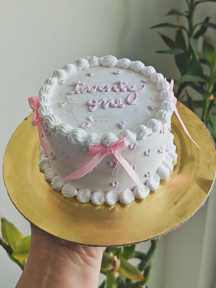 A delicate white and pink cake for a twenty-first birthday. I used tiny pink hearts, bows, and piped lettering to create a sweet and feminine design. This one was a Dark Chocolate Mousse flavor.
