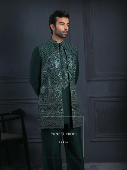 An emerald kurta set paired with a sleeveless embroidered jacket. Subtle geometric patterns and paisley accents flow across the rich green fabric, reflecting understated luxury.