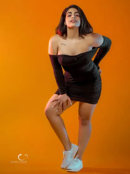 A black dress against a bold orange background creates a stunning color contrast. This portrait is about power, attitude, and owning your space.