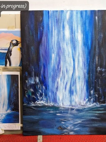 A work in progress shot of a dramatic blue waterfall. The reference image is placed next to the canvas, showing the process of interpretation and creation.