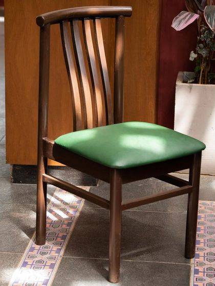 A custom-designed wooden chair with a green upholstered seat. We work closely with furniture makers to create bespoke pieces that perfectly match the material palette and design intent of our projects.