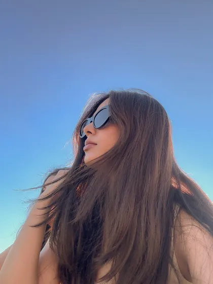 A close-up, artistic selfie against the bright blue sky at the beach.