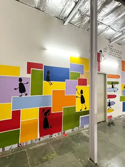 Transforming a school corridor in Dharavi into a vibrant world of color and movement. This community mural uses simple stick figures and bold geometric shapes to tell a story of joy and togetherness, turning a plain hallway into an inspiring space for students.