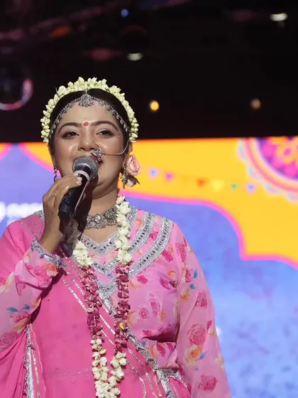 Another angle of me hosting as Radha, with the event branding visible in the background.