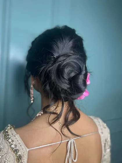 A back view of the elegant reception hairstyle. The messy bun is adorned with flowers, adding a touch of romance.