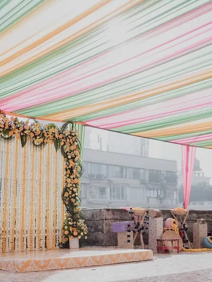 A simple and elegant Haldi setup for a home wedding. We used a colorful pastel drape ceiling and a traditional marigold backdrop.