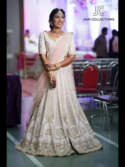 A client looking graceful in a white and gold embroidered lehenga at her event.