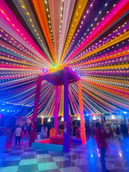 A spectacular ceiling decoration for a Sangeet or Mehendi night. The canopy of colorful drapes is interwoven with fairy lights, creating a mesmerizing, star-like effect over the dance floor.