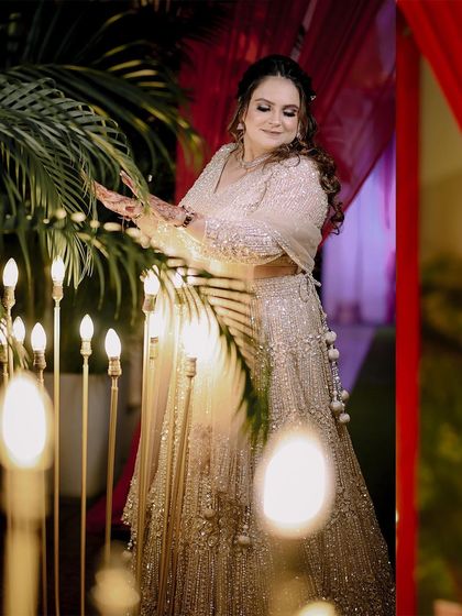 A beautiful portrait of the bride, Pooja, during her engagement ceremony, surrounded by warm, decorative lights.