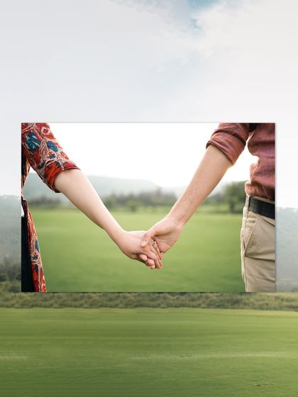 A minimalist and symbolic pre-wedding shot focusing on the couple holding hands against a vast, natural landscape. This image represents their journey together.