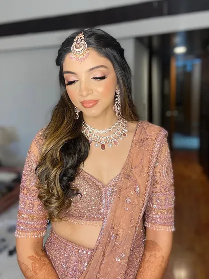 A soft and romantic look for Hetal's engagement. The makeup features pink tones and a luminous finish to match her beautiful peach lehenga.