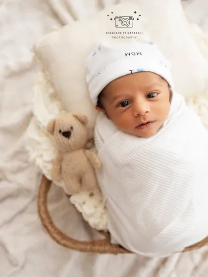 An alert newborn wearing a "I love Mom" hat looks directly at the camera. We capture both sleeping and awake moments to show your baby's budding personality.