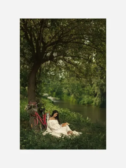Another angle of the peaceful reading scene, this shot captures the lush greenery and the tranquil riverside setting, adding to the storybook quality of the portrait.