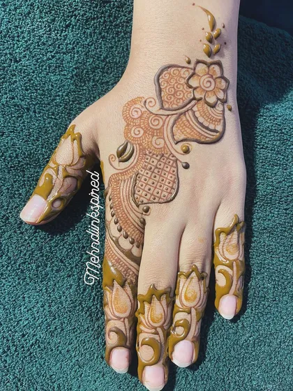 An example of our elegant and simple Arabic mehndi style. This design flows beautifully along the back of the hand, featuring a central floral element with delicate shading and lotus details on the fingers.
