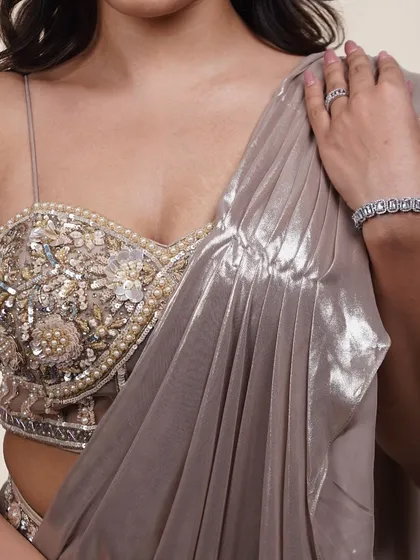 A close-up of the embellished blouse of our metallic pre-draped saree. The intricate beadwork and pearl details are simply stunning.