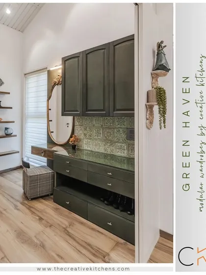 A view into the "Green Haven" walk-in wardrobe. This image highlights the custom dressing area, with pine green cabinetry, a glass top, and specialized storage for shoes and accessories, all framed by a beautiful antique-style mirror.