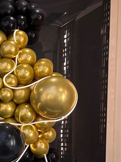 A detail shot of a gold and black balloon garland. The use of high-shine chrome balloons gives the decoration a luxurious and modern feel.