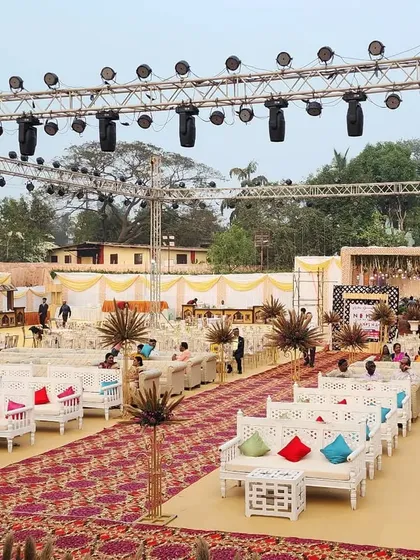 A wide view of a large-scale outdoor reception setup. We arranged comfortable lounge seating with colorful cushions, ensuring guest comfort without sacrificing the event's grand and festive aesthetic.